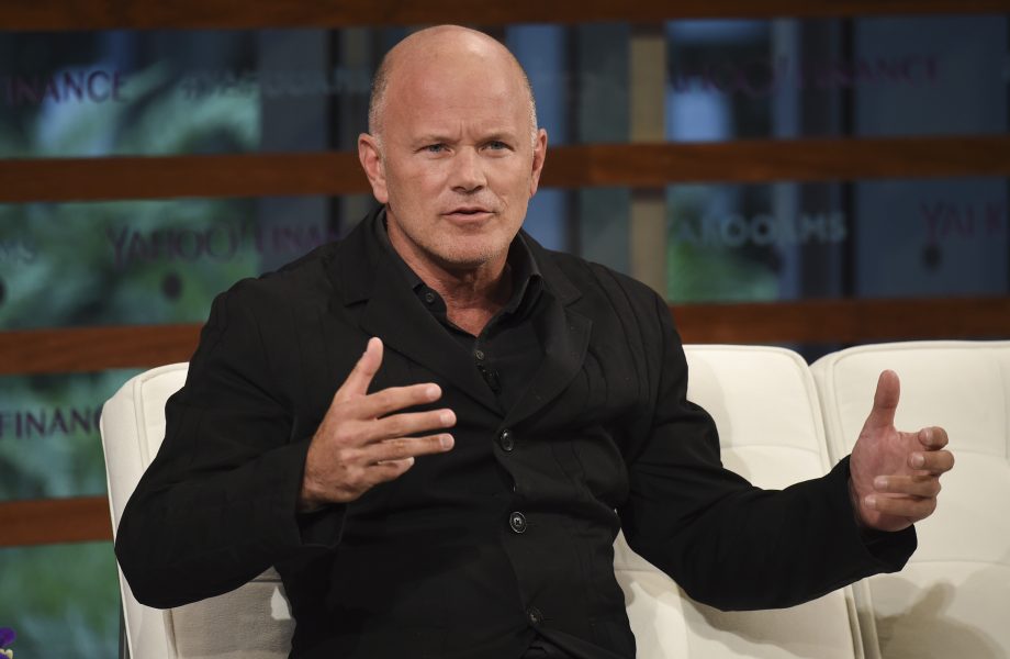 Mike Novogratz in einem schwarzen Anzug sitzt auf einer weißen Couch und gestikuliert mit den Händen, während er in einem Interview oder einer Podiumsdiskussion über Solana spricht.