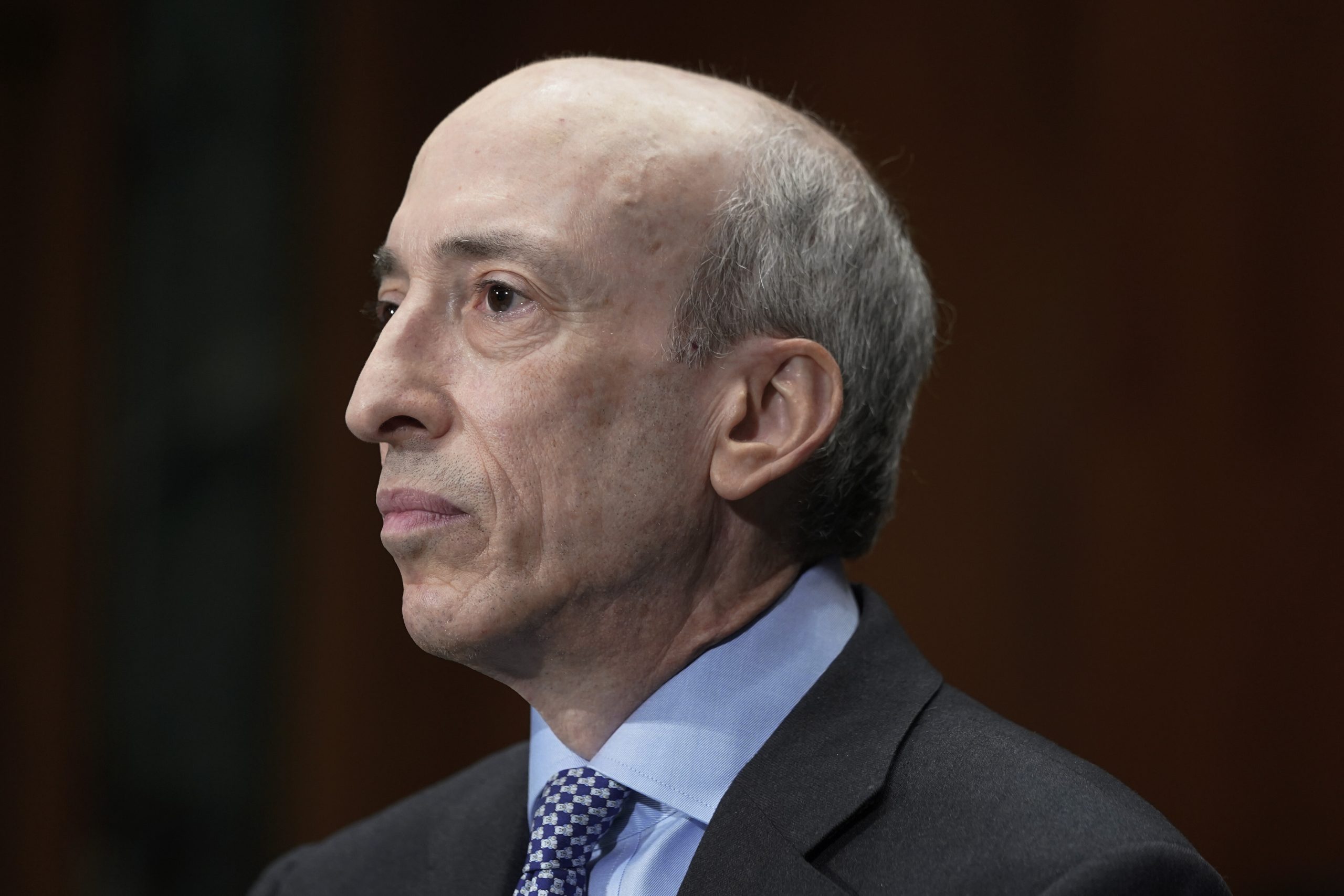 Gary Gensler in Anzug und Krawatte mit ernstem Gesichtsausdruck ist im Profil vor einem dunklen Hintergrund abgebildet und ähnelt Gary Gensler.