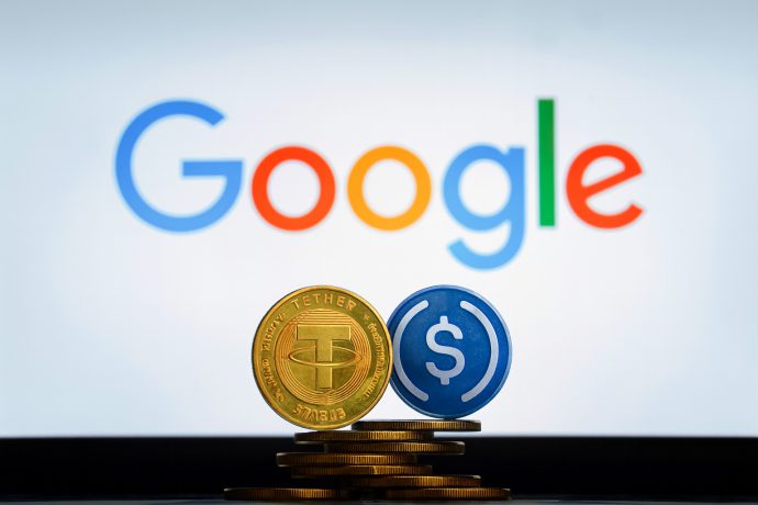 Zwei Stapel Münzen mit den Logos von Tether und USD Coin werden vor einem Google-Logo auf einem Bildschirm angezeigt.