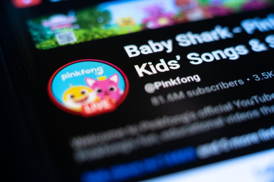 Nahaufnahme der Pinkfong-YouTube-Kanalseite auf einem Bildschirm mit dem Profilbild, dem Kanalnamen, der Abonnentenzahl und einer Erwähnung von Baby Shark Token in den Videobeschreibungen.