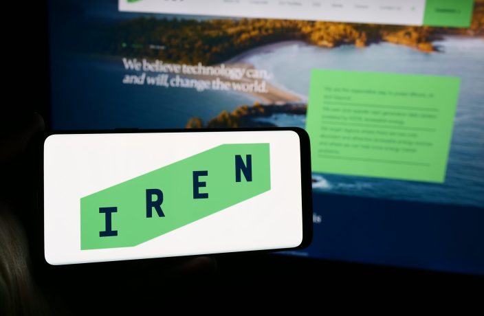 Ein Smartphone zeigt das IREN-Logo vor einem Computerbildschirm, der die IREN-Website in grüner und weißer Farbgebung zeigt, während das Interesse an Angeboten wie CoinShares Bitcoin Mining ETF am Rekordhoch ist und immer mehr Anleger einsteigen.