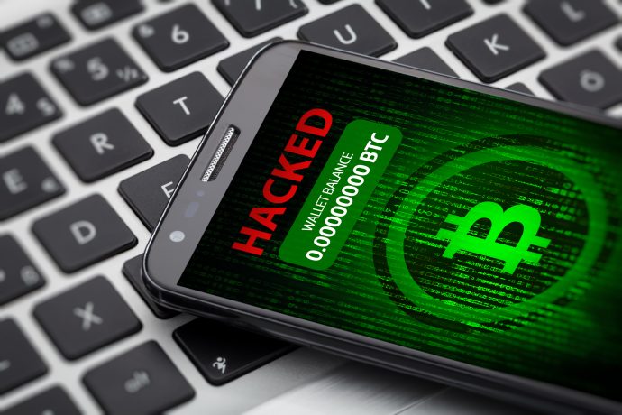 Ein Smartphone mit einer HACKED-Warnung und einem Bitcoin-Guthaben von Null liegt auf der Tastatur eines Laptops und weist auf die Gefahren hin, die von Quantencomputern ausgehen.
