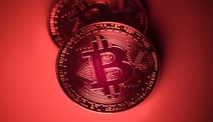 Zwei physische Bitcoin-Token (BTC) werden unter rotem Licht gezeigt, wobei auf ihrer Oberfläche kreislaufähnliche Muster zu erkennen sind, die das digitale Wesen von Bitcoin hervorheben.