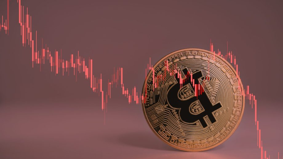 Eine physische Bitcoin-Münze wird mit einem roten, abwärts gerichteten Aktienchart überlagert, der den Wertverfall der Kryptowährung und seine Auswirkungen auf Bitcoin Treasury Firmen und ihre Strategie hervorhebt.