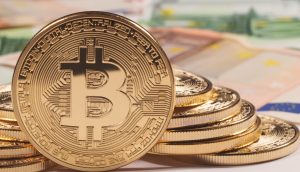 Ein Stapel goldfarbener Bitcoin-Token wird vor unscharfen Euro-Banknoten gezeigt, um die Attraktivität von Krypto-Vermögenswerten und Überlegungen wie Jahreshaltefrist für Anleger zu unterstreichen.