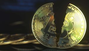 Ein goldfarbener Bitcoin-Token wird in zwei Hälften geteilt gezeigt, was auf einen Rückgang oder eine Krise der Kryptowährung hindeutet - ein Echo auf die Bedenken über 14 verlorene Bitcoins. Andere Münzen liegen unscharf im Hintergrund.