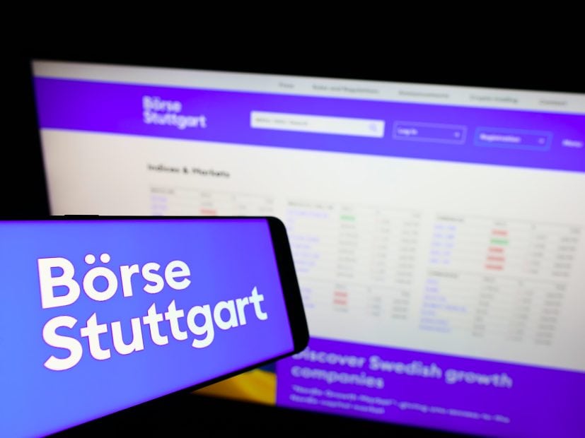 Ein Smartphone zeigt das Logo der Boerse Stuttgart Digital vor einem Computerbildschirm, auf dem die Website der Börse Stuttgart mit Finanzdaten angezeigt wird, um die Verbindungen zwischen Deutschland und Finanzmärkten wie Spanien hervorzuheben.