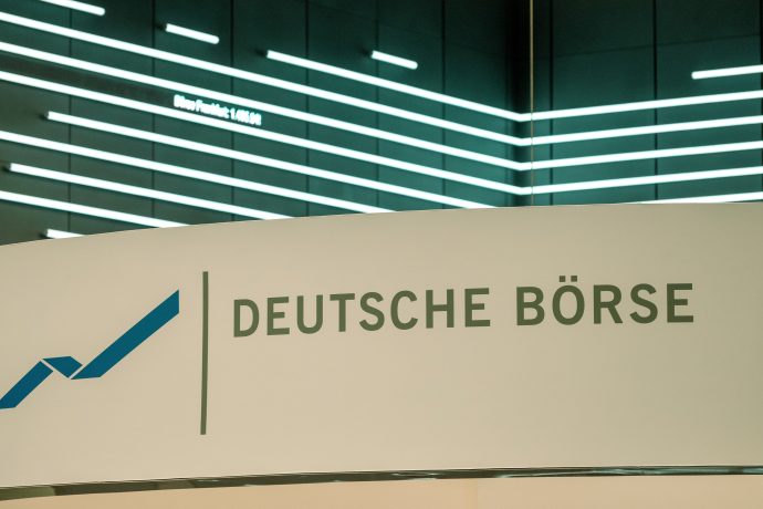 Ein Schild mit dem Logo und dem Namen der Deutschen Börse vor einer modernen, beleuchteten Wand mit horizontalen Lichtbändern unterstreicht den Fokus auf Innovation und Integration, einschließlich der Entwicklungen bei Stablecoins.