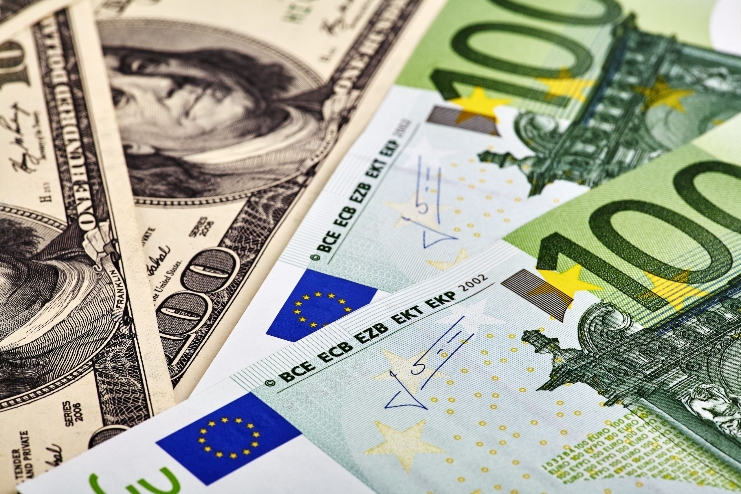 Nahaufnahme mehrerer 100-US-Dollar-Scheine und 100-Euro-Banknoten, die nebeneinander ausgelegt sind, wobei die detaillierten Designs hervorgehoben werden - ein ideales Anschauungsmaterial für Themen wie Euro-Stablecoins und internationale Währungsvergleiche.