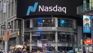 Menschen gehen vor dem Nasdaq MarketSite-Gebäude am Times Square in New York City spazieren, über dem ein großes digitales Nasdaq-Zeichen prangt, in der Nähe von Gemini, der von den Winklevoss-Zwillingen gegründeten Krypto-Börse, die an Bekanntheit gewonnen hat.