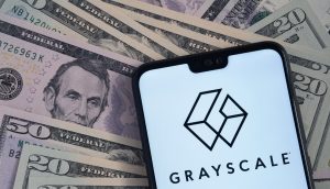Ein Smartphone zeigt das Grayscale-Logo und den Namen auf verstreuten US-amerikanischen Zwanzig- und Fünf-Dollar-Scheinen - und unterstreicht damit die Bedeutung des Multi-Asset-Krypto-Spot-ETF von Grayscale in der Welt der digitalen Finanzen.
