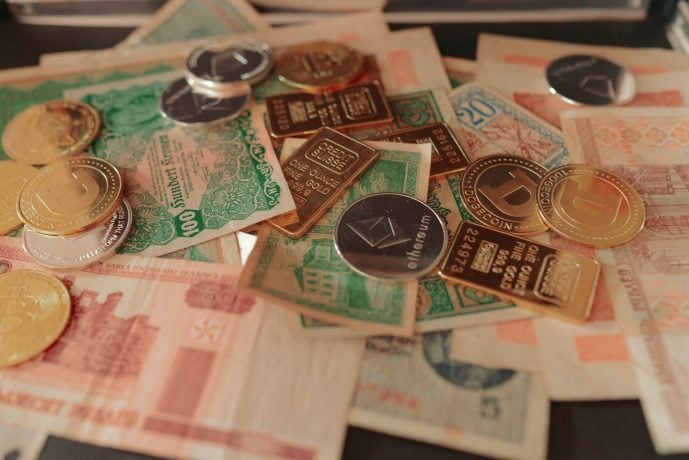 Verschiedene Papierwährungen, Gold- und Silberbarren und Kryptowährungsmünzen sind auf einer Fläche verstreut - eine faszinierende Mischung für Krypto-Anleger, die Sicherheit und Alternativen zum klassischen Tagesgeld suchen.