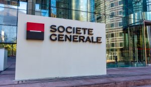 Ein Schild mit dem Logo und dem Namen der Société Générale steht vor einem gläsernen Bürogebäude und weist auf die bullische Expansion des Unternehmens in regulierte Dollar-Stablecoin-Angebote wie Société Générales USDCV hin.