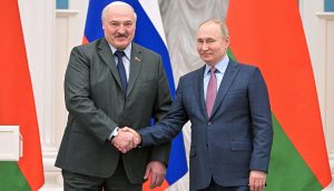 Zwei Männer im Anzug schütteln sich die Hände und posieren für ein Foto vor russischen und belarussischen Flaggen, während der weißrussische Präsident mit seinem Amtskollegen über Sanktionen und Kryptonutzung spricht.
