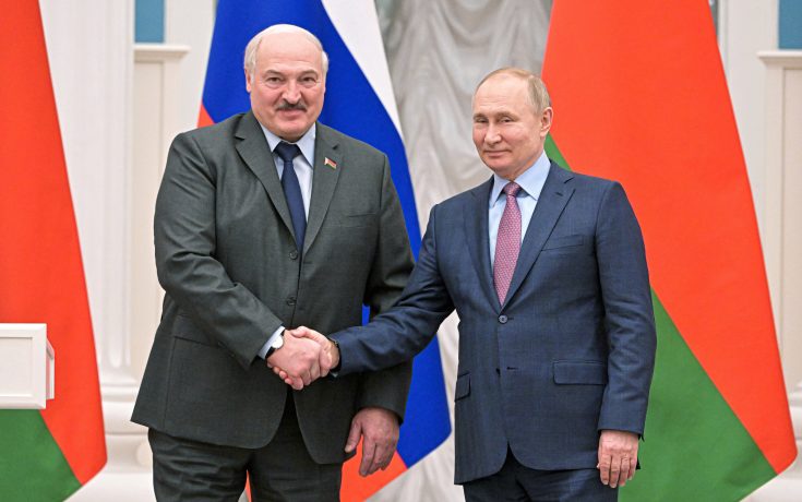 Zwei Männer im Anzug schütteln sich die Hände und posieren für ein Foto vor russischen und belarussischen Flaggen, während der weißrussische Präsident mit seinem Amtskollegen über Sanktionen und Kryptonutzung spricht.