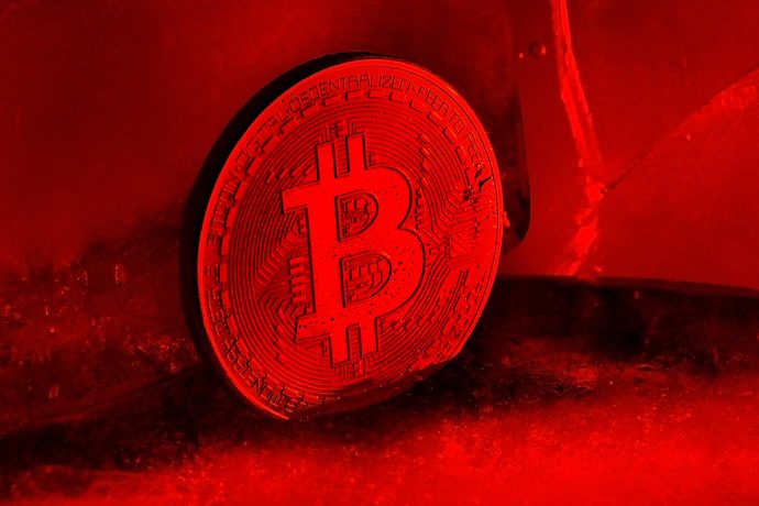 Eine Bitcoin-Münze mit Krypto-Thema wird unter leuchtend roter Beleuchtung angezeigt, die das Bitcoin-Symbol und das schaltungsähnliche Design hervorhebt.