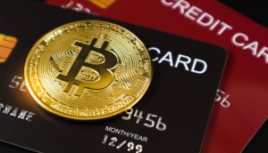 Ein goldener Bitcoin-Token ruht auf zwei gestapelten Kreditkarten und verdeutlicht die Überschneidung von Bitcoin und traditionellen Finanzsystemen.