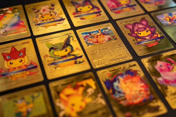 Eine Nahaufnahme mehrerer glänzender, goldfarbener Pokémon-Karten, die in Reihen auf einer dunklen Fläche ausgestellt sind und auf das einzigartige Potenzial des Handels mit diesen Sammlerstücken an der Kette hinweisen.