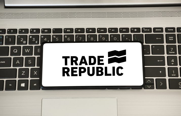 Ein Smartphone mit dem Logo Trade Republic liegt auf der Tastatur eines Laptops: ein Symbolbild für den Trade Republic Sparplan.