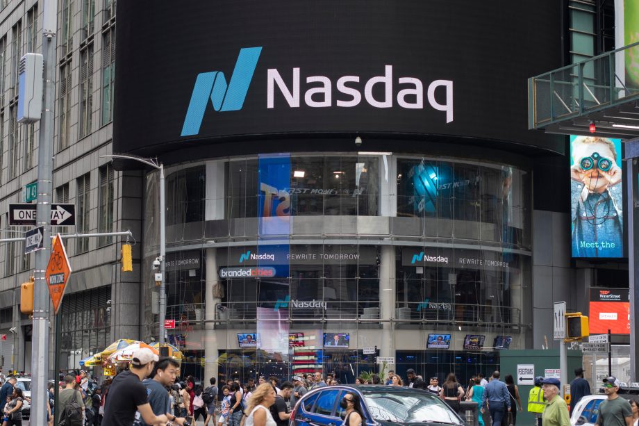 Straßenansicht des Nasdaq MarketSite-Gebäudes am Times Square, New York City, mit den großen Logos von Nasdaq und Securitize auf einem LED-Bildschirm über dem regen Fußgängerverkehr.