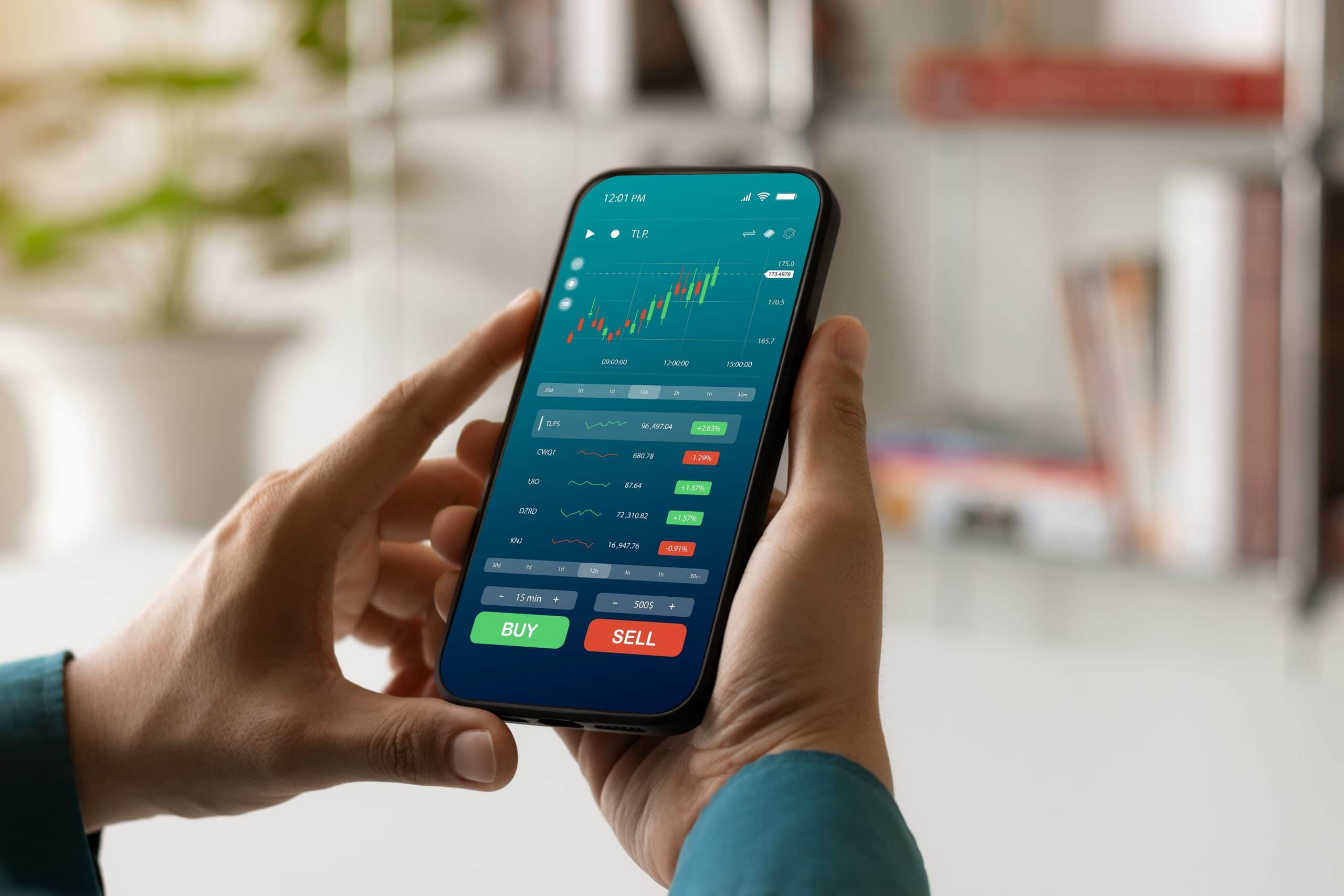 Eine Person hält ein Smartphone in der Hand, auf dem eine Trading-App mit Aktien-Charts und Kauf-/Verkaufsoptionen angezeigt wird.