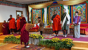 Eine feierliche Zeremonie mit Menschen in traditioneller Kleidung auf einer geschmückten Bühne; eine Person verbeugt sich, während sie eine Urkunde erhält, was die Bedeutung der digitalen Identität in modernen Kontexten unterstreicht.