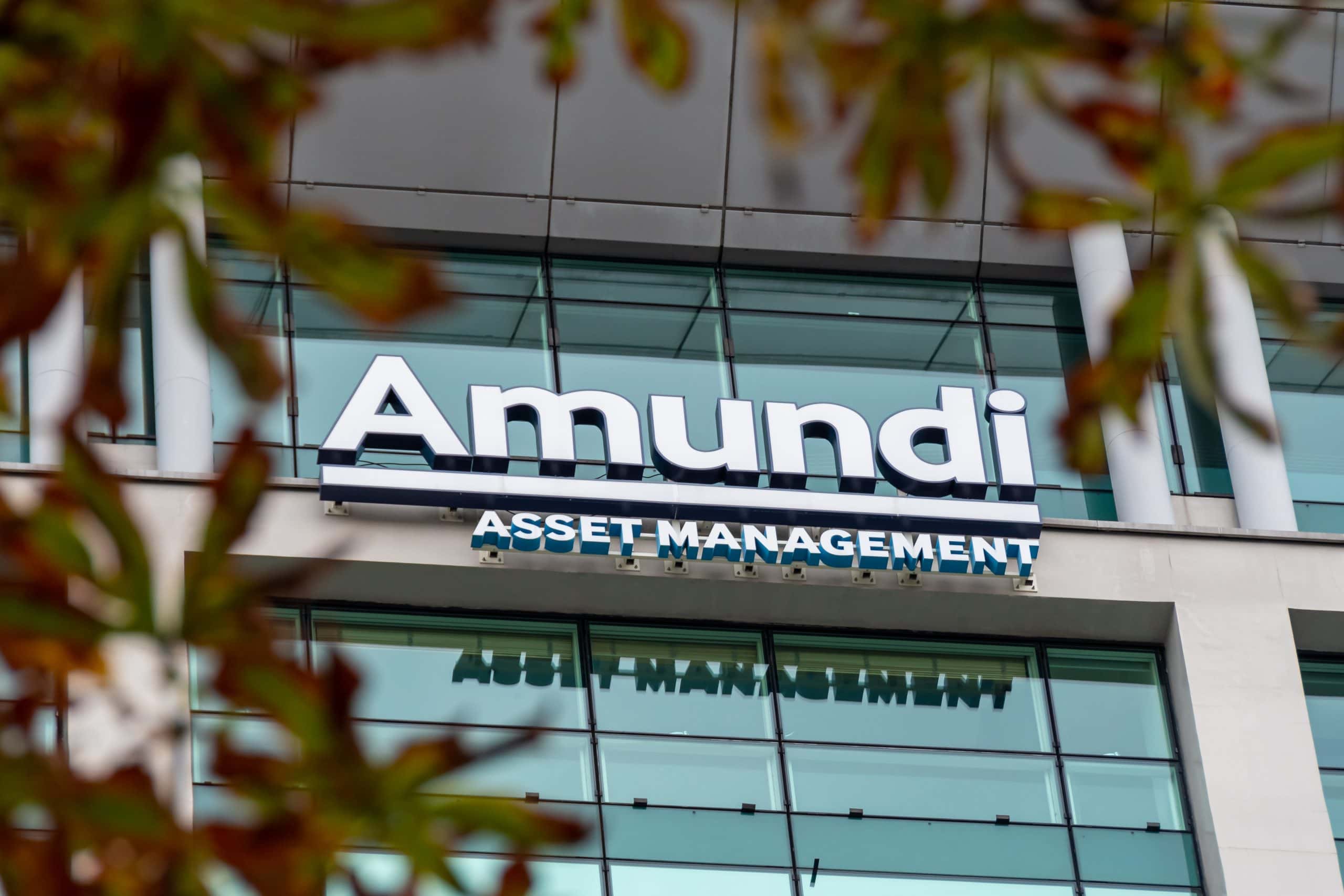 Das Äußere eines Bürogebäudes von Amundi Asset Management mit dem Firmenschild, das durch einige unscharfe Äste sichtbar ist, spiegelt die aktive Rolle des Unternehmens auf dem europäischen Markt wider, da neue MiCA-Regeln und Bitcoin-ETN-Trends die Finanzlandschaft prägen.