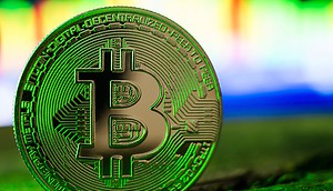 Bitcoin dreht auf Eine physische Bitcoin-Münze steht aufrecht auf einer Fläche, die ihren Wert symbolisiert, während sich der Kurs gegenüber dem US-Dollar verändert, vor einem verschwommenen, bunten Hintergrund.