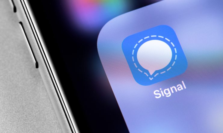 Nahaufnahme eines Smartphone-Bildschirms mit dem Signal-App-Symbol, das einen blauen Hintergrund mit einer weißen Sprechblase als Symbol für sichere Kommunikation zeigt.