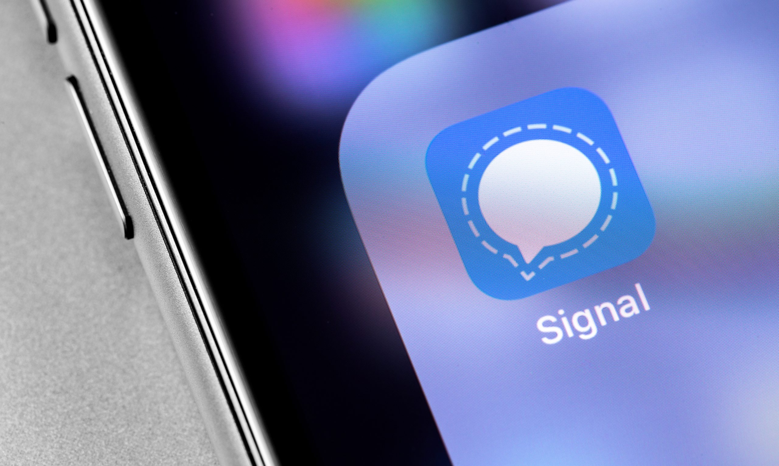 Nahaufnahme eines Smartphone-Bildschirms mit dem Signal-App-Symbol, das einen blauen Hintergrund mit einer weißen Sprechblase als Symbol für sichere Kommunikation zeigt.