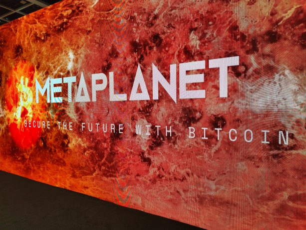 Auf einer großen digitalen Anzeige ist METAPLANET und SECURE THE FUTURE WITH BITCOIN vor einem feurigen, abstrakten Hintergrund zu lesen, der die kühne Vision von Metaplanet wiedergibt.