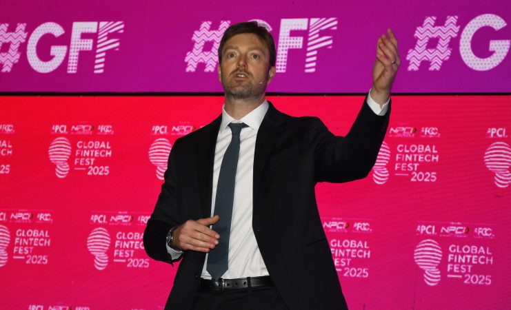 PayPal-CEO Alex Chriss präsentiert die neue KI-Strategie auf dem Global Fintech Fest 2025 Alex Chriss gestikuliert, während er auf der Bühne des Global Fintech Fest 2025 spricht, während hinter ihm Bildschirme mit PayPal- und Veranstaltungslogos zu sehen sind.