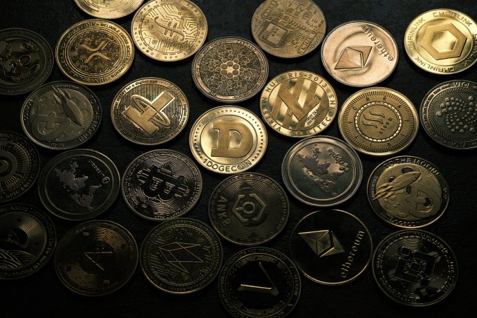 Können Altcoins jetzt profitieren? Eine Sammlung verschiedener physischer Münzen, die Kryptowährungen wie Bitcoin, Ethereum, Dogecoin und andere Altcoins repräsentieren - und den Geist der Altcoin-Saison perfekt einfangen - dicht aneinandergereiht auf einer dunklen Oberfläche.