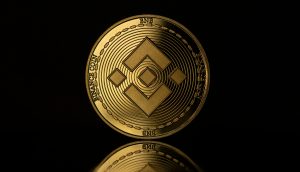 <a href='https://market.bitrss.com/coin/binancecoin' rel='noopener' target='_blank' class='crypto-highlight' title='BNB Market Overview'>BNB ($1,141.66)</a> trotzt dem Marktcrash Eine goldfarbene BNB-Münze mit dem Binance-Logo steht aufrecht vor einem dunklen Hintergrund, ihr Bild spiegelt sich auf einer glänzenden Oberfläche.