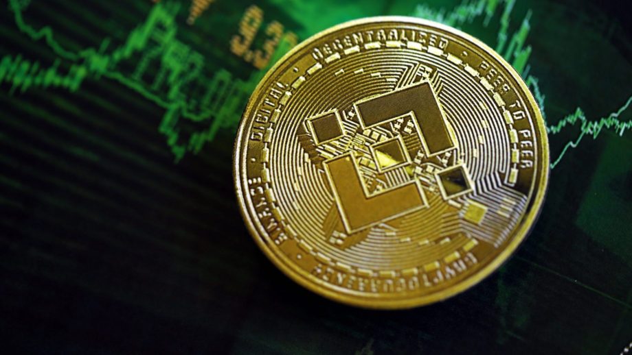 Eine BNB-Kryptowährungsmünze ruht auf einem digitalen Finanzdiagramm, das schwankende grüne Marktlinien und Zahlen anzeigt.