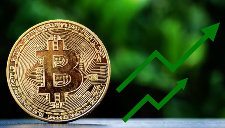 Eine physische Bitcoin-Münze steht aufrecht auf einer Fläche mit einem grünen, nach oben zeigenden Pfeil auf der rechten Seite, der den steigenden Wert von Bitcoin vor einem verschwommenen grünen Hintergrund symbolisiert.