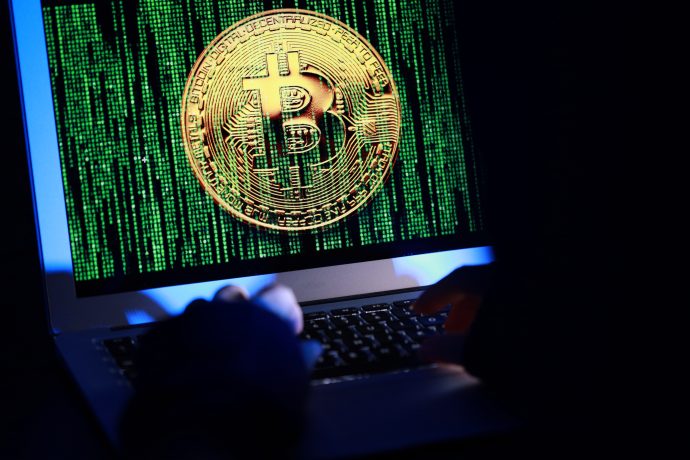 Die Grafik zeigt das Bitcoin-Logo auf einem Bildschirm, was eine Attacke auf Bitcoin symbolisieren soll