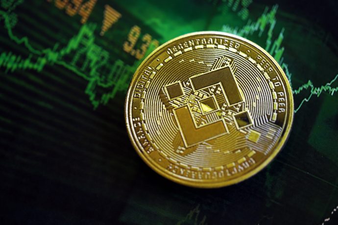 Eine Binance-Münze (BNB) ruht auf einem digitalen Bildschirm, der grüne Finanzgraphen und numerische Daten anzeigt, die den Kryptowährungshandel und die BNB-Marktanalyse symbolisieren.