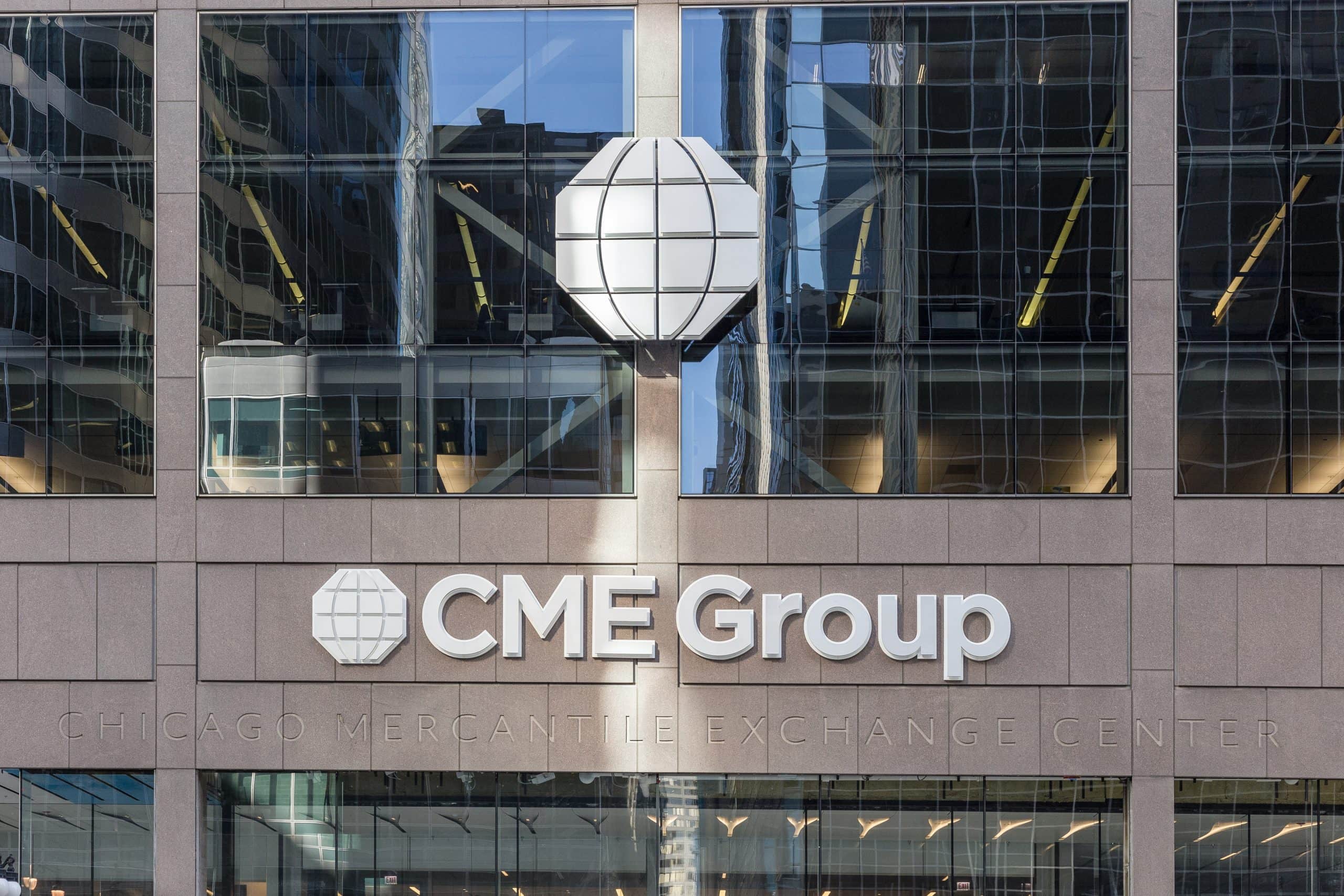 Gebäudefassade mit dem Logo der CME Group und dem Schriftzug "Chicago Mercantile Exchange Center" mit Glasfenstern, die nahe gelegene Strukturen widerspiegeln - ein Knotenpunkt, an dem traditionelles Finanzwesen auf Krypto-Innovation trifft.