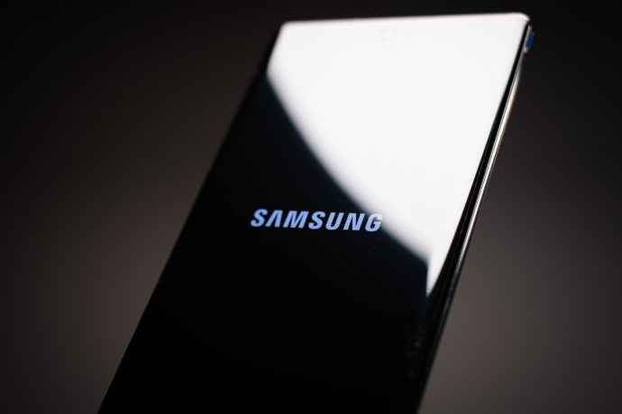 Nahaufnahme eines Samsung-Smartphones, auf dessen Bildschirm das Samsung- und das Coinbase-Logo vor einem dunklen Hintergrund zu sehen sind.