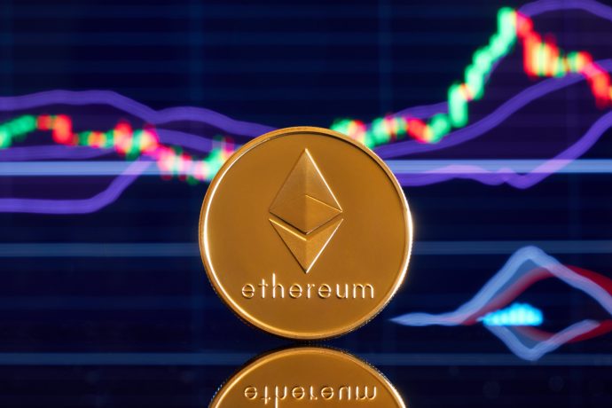 Eine goldene Ethereum-Münze steht aufrecht vor einem digitalen Bildschirm, der bunte Ethereum-Finanzcharts und -Grafiken anzeigt.