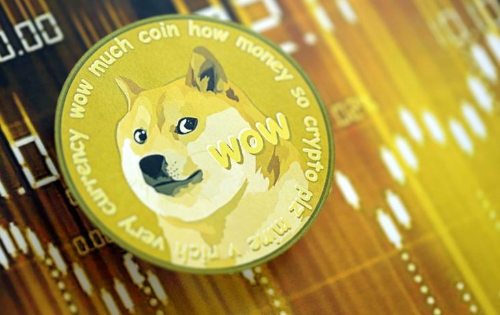 Eine physische Dogecoin-Münze mit dem kultigen Logo und den Meme-Sprüchen sitzt auf einem unscharfen Kryptowährungspreisdiagramm in Gelb- und Brauntönen.
