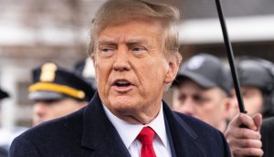 Donald Trump bestätigt, dass sich China und die USA in einem Handelskirieg befinden Ein Mann mit dunklem Mantel und roter Krawatte steht im Freien und blickt zur Seite, während im Hintergrund Menschen und ein Polizeibeamter auftauchen - ein Abbild der angespannten Stimmung inmitten der laufenden Handelskriegsgespräche.