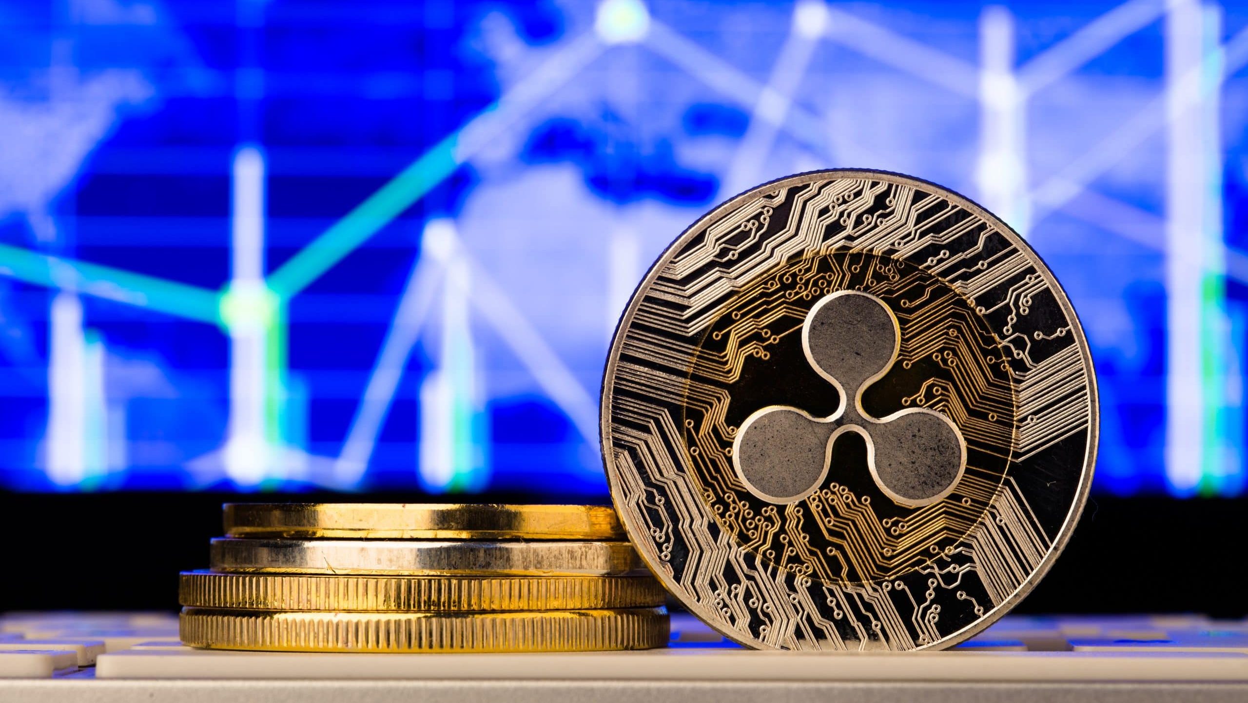 Ein Stapel Goldmünzen und eine Münze der Kryptowährung XRP werden vor einer blauen digitalen Weltkarte mit Finanzgrafiken angezeigt.