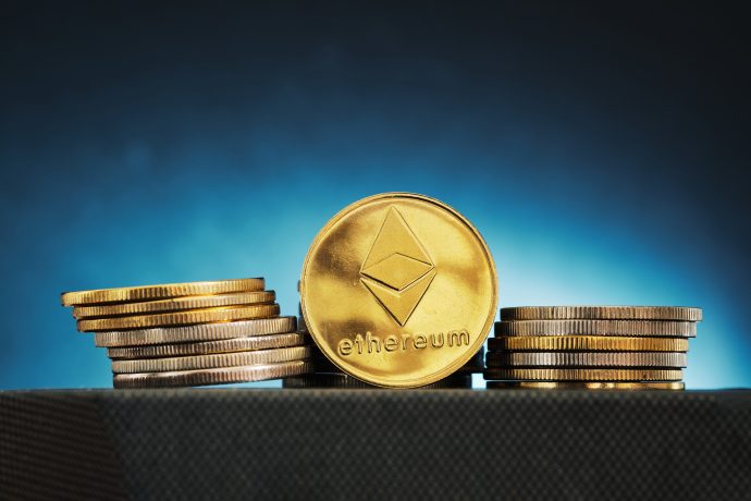 Eine goldene Ethereum-Münze mit dem Ethereum-Logo steht zwischen Münzstapeln vor einem Hintergrund mit blauem Farbverlauf - ein Symbol der Chancen für Investoren auch in Zeiten der Marktschwäche.
