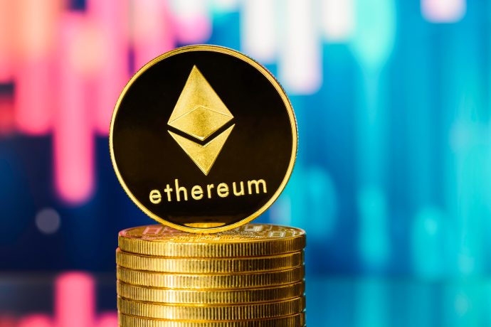 Ein Stapel Goldmünzen mit einer physischen Ethereum-Münze obenauf, die das Ethereum-Logo und den Text vor einem lebhaften, bunten, verschwommenen Hintergrund zeigt.