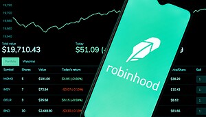 Ein Smartphone zeigt das Logo der Robinhood-App vor einem Computerbildschirm mit Börsendaten und einem steigenden Robinhood-Liniendiagramm.