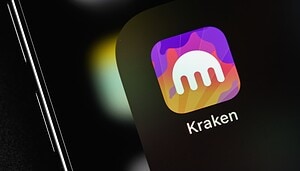 Nahaufnahme eines Smartphone-Bildschirms, auf dem das Kraken-App-Symbol mit dem unverwechselbaren Kraken-Logo in Weiß vor einem farbenfrohen Hintergrund angezeigt wird.