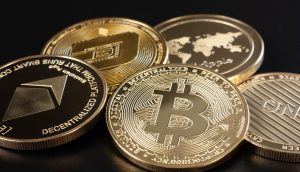 Eine Nahaufnahme verschiedener physischer Krypto-Münzen, darunter Bitcoin, Ethereum und Dash, die auf einer dunklen Oberfläche angezeigt werden.