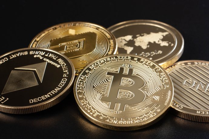 Eine Nahaufnahme verschiedener physischer Krypto-Münzen, darunter Bitcoin, Ethereum und Dash, die auf einer dunklen Oberfläche angezeigt werden.